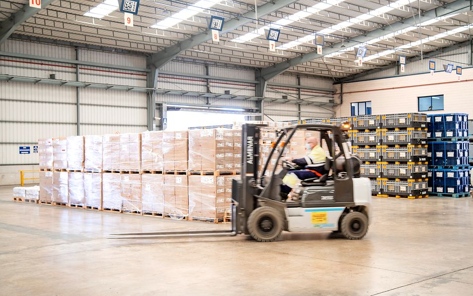 Warehouse with goods and a forklift in motion 