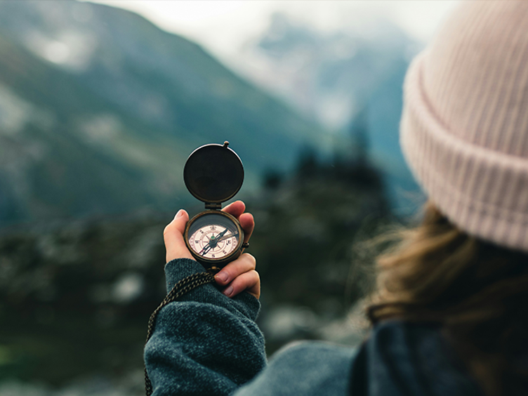Girl facing away, holding a compass 